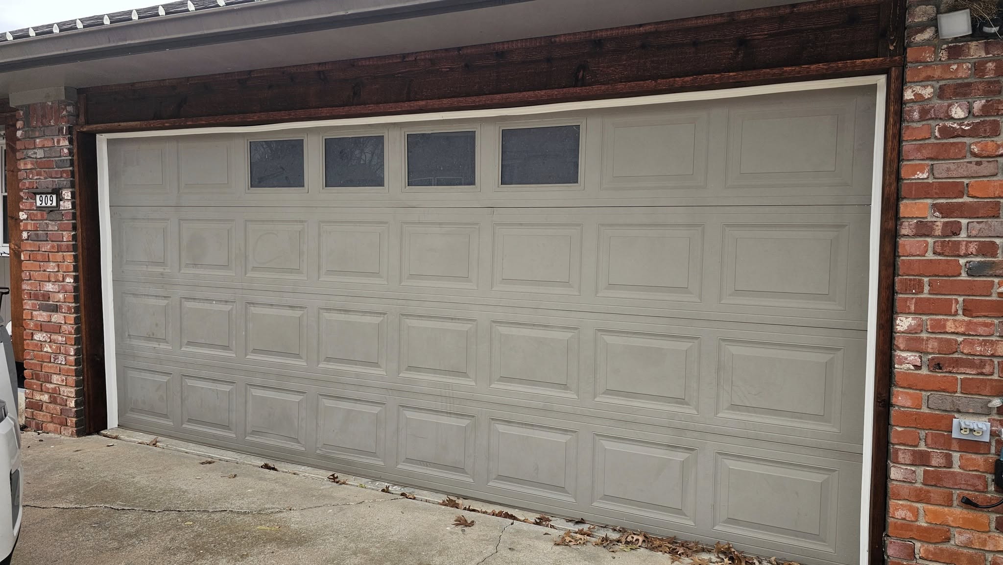 A garage door with windows is shown on a brick house.
