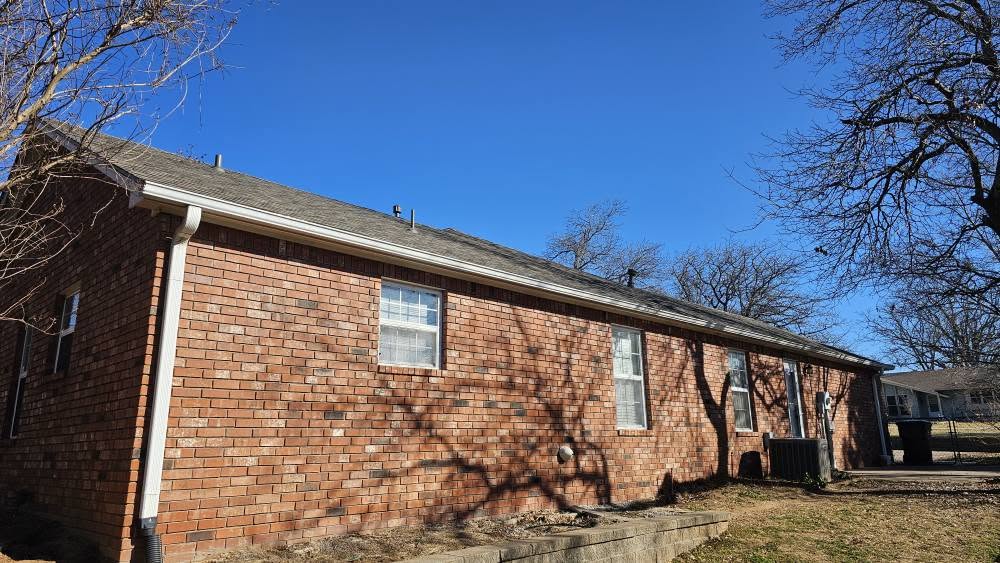 A brick house with a clear blue sky and bare trees.
