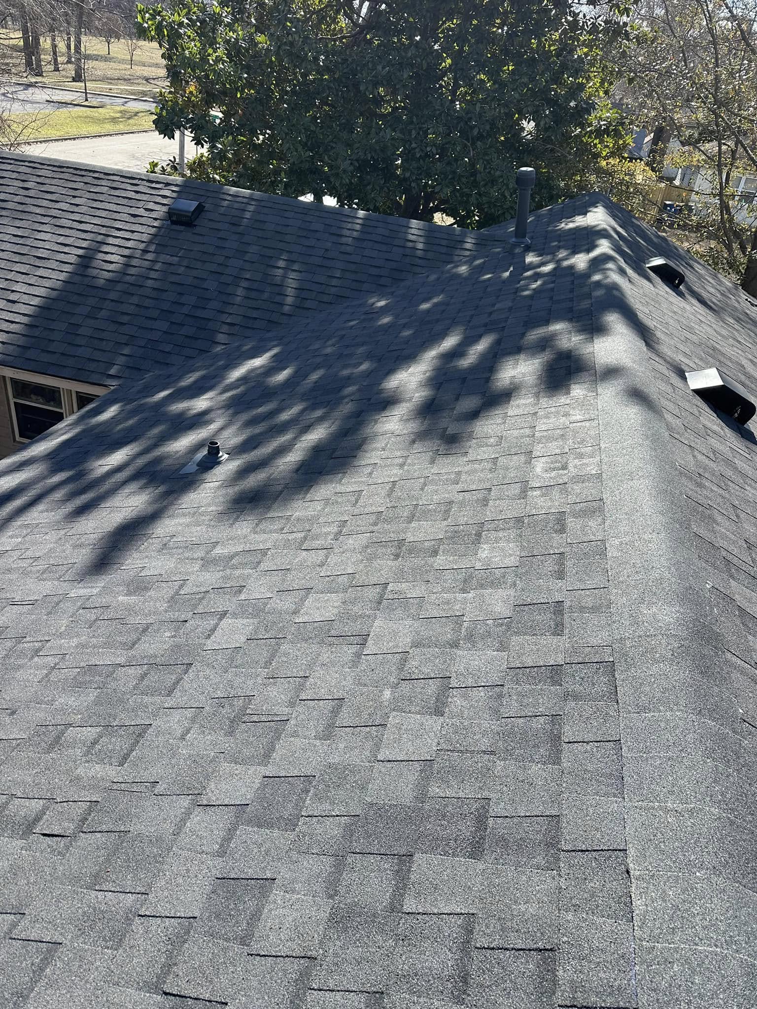 A grey asphalt shingle roof with several vents and a chimney is shown from above.
