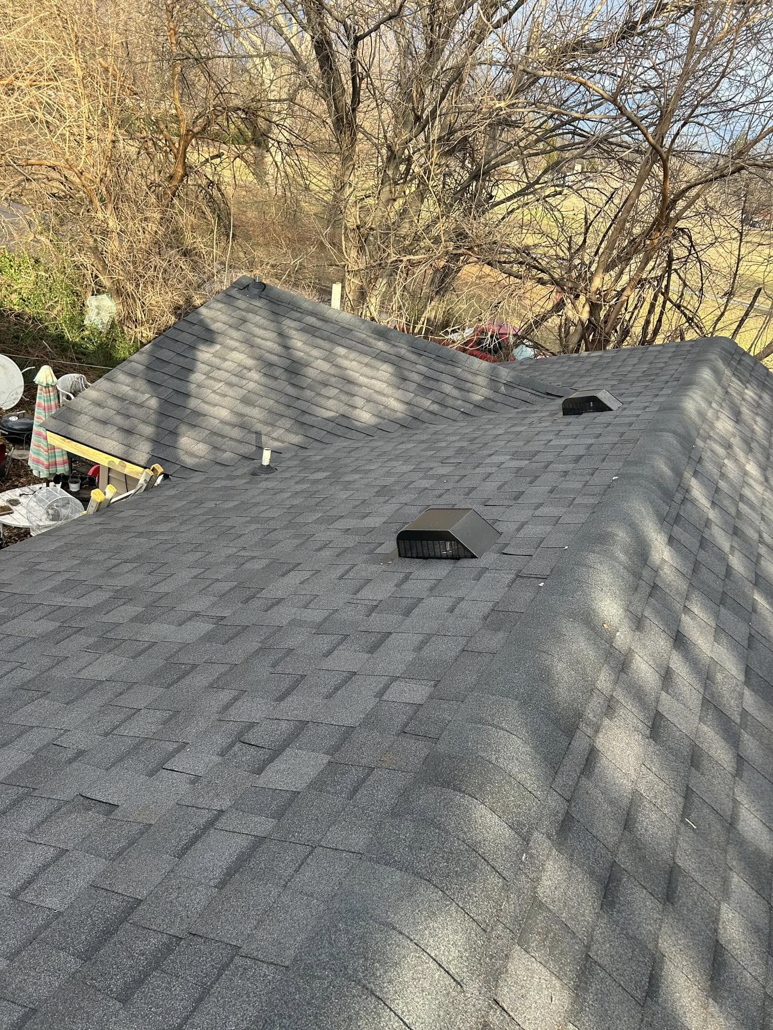 A gray asphalt shingle roof with two vents is shown outdoors.