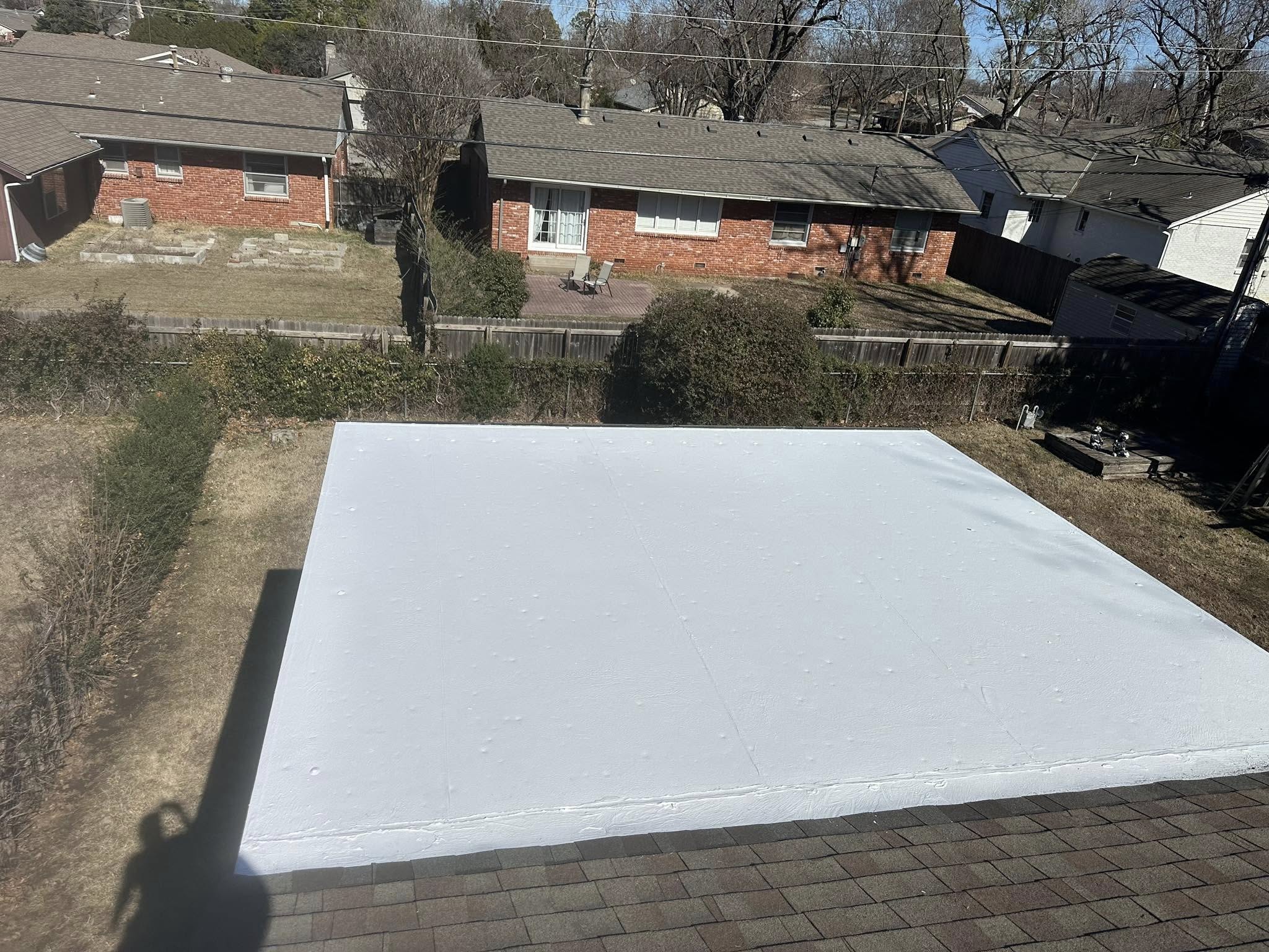 A white flat roof is shown in a suburban backyard with houses and trees.