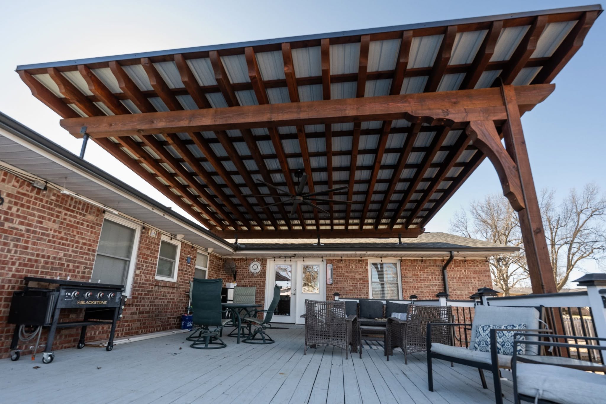 A backyard patio with a covered pergola, grill, and seating area.