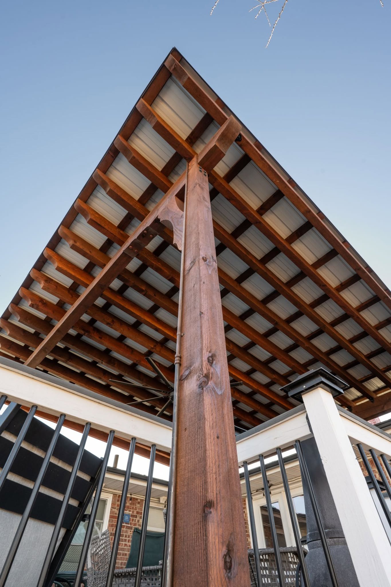 A wooden pergola with a metal roof is shown outdoors.