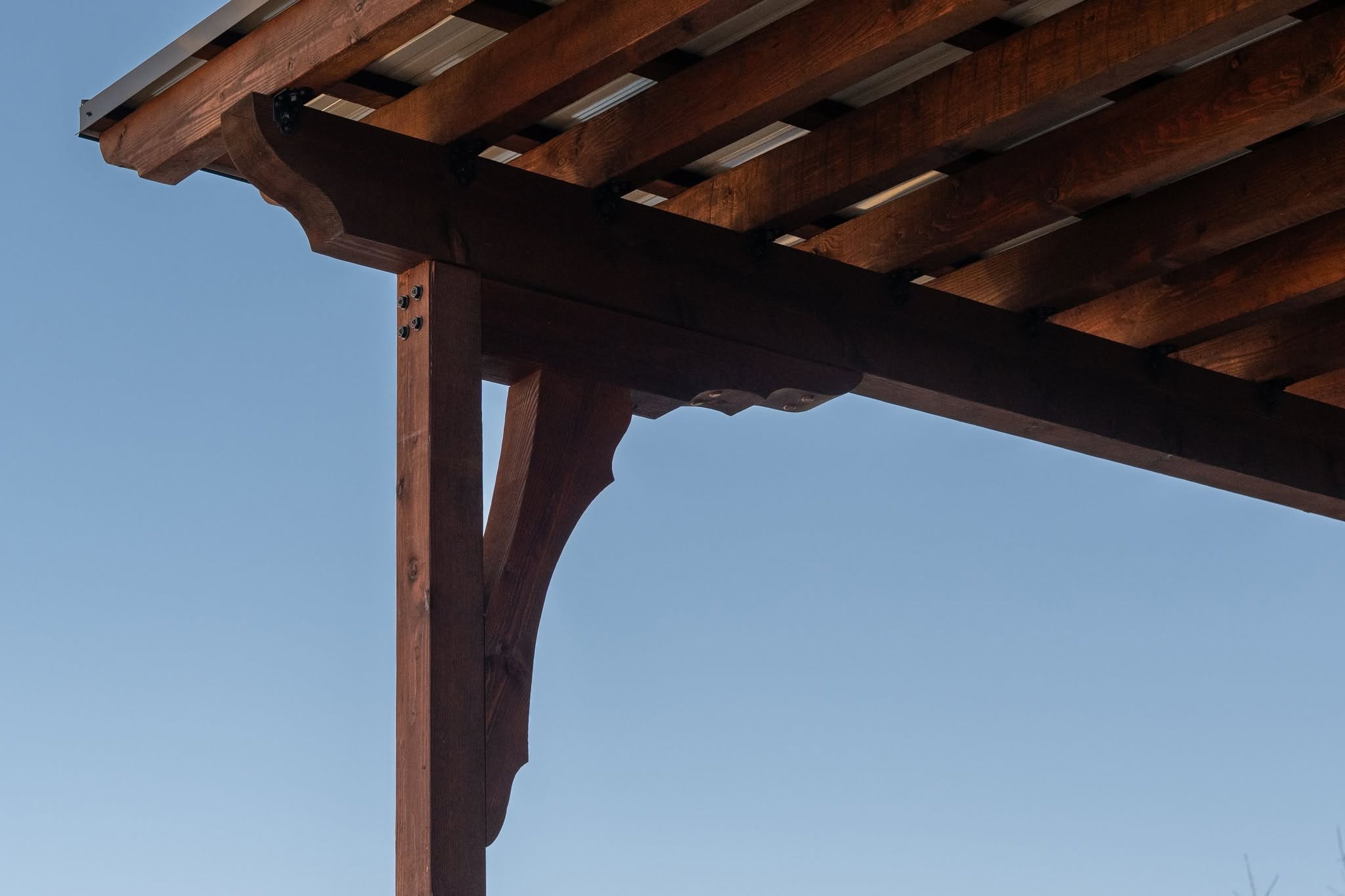 A wooden pergola structure is shown against a clear blue sky.