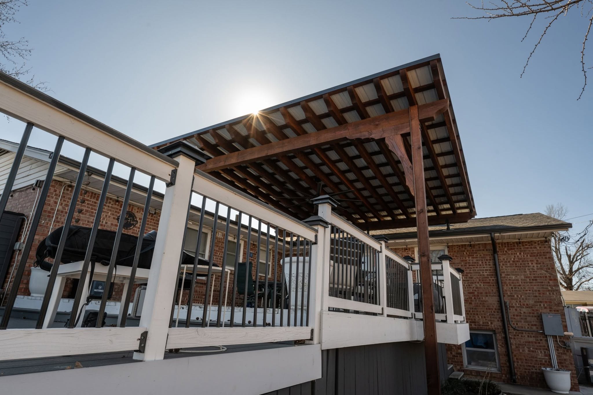 A backyard deck with a metal roof pergola is shown.
