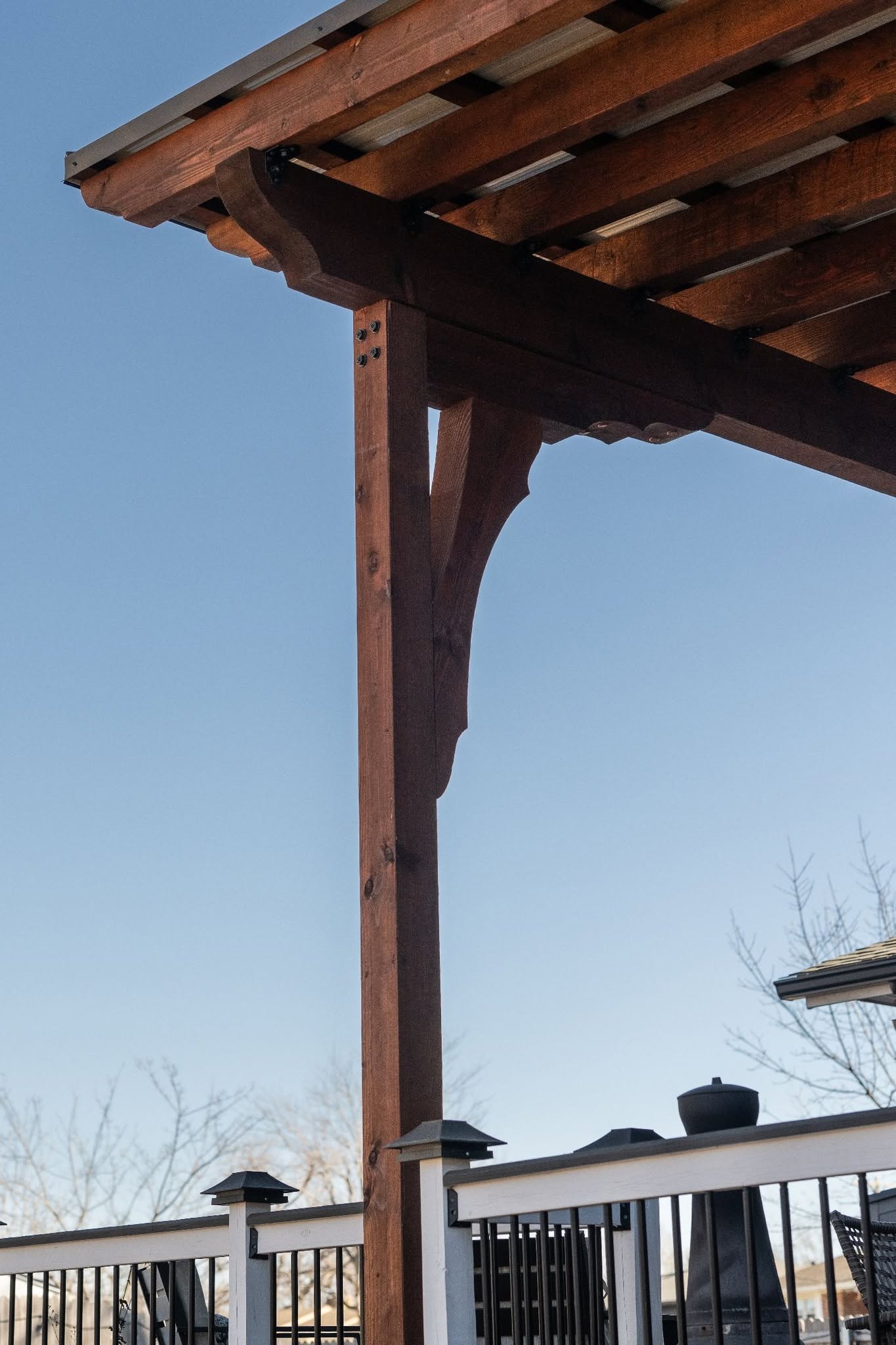 A wooden pergola stands over a deck with a clear blue sky.
