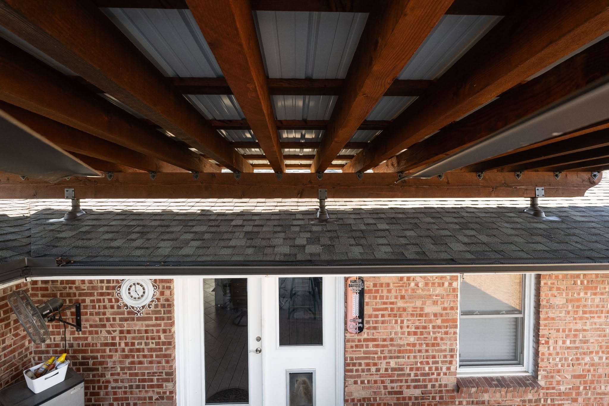 A covered patio with a brick wall, doors, and a window.