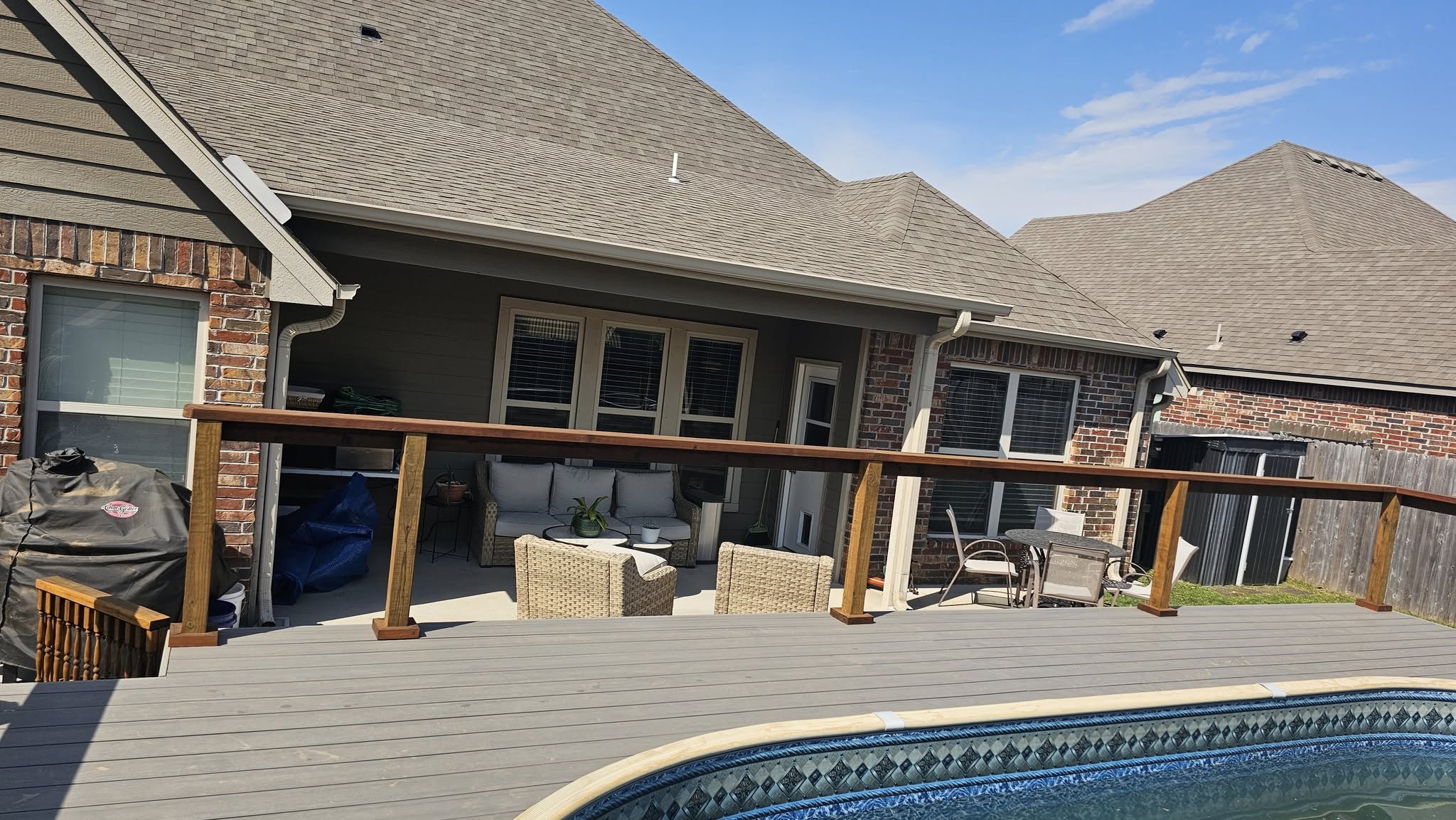 A backyard deck with a pool, furniture, and a grill is shown.