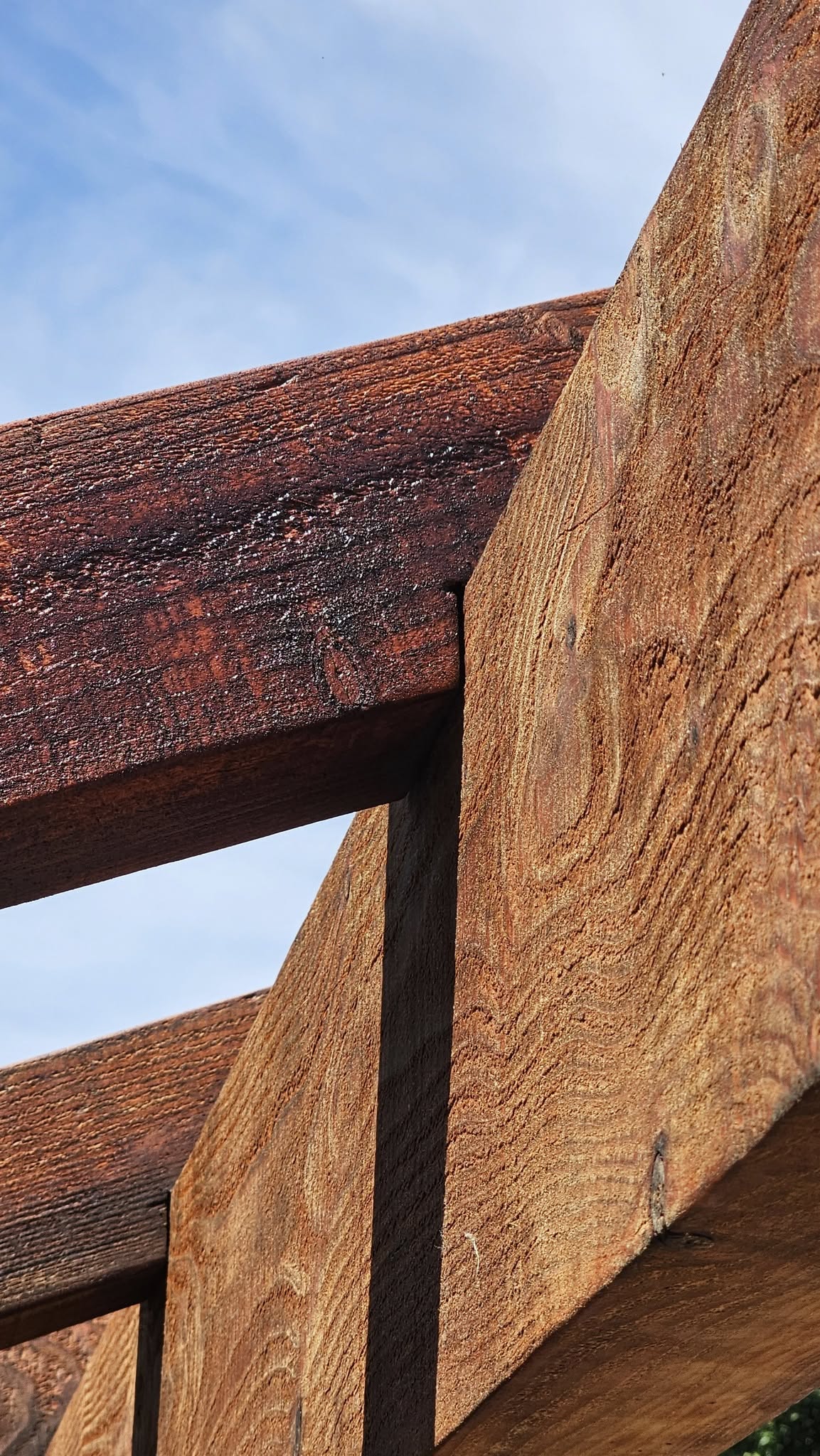 Wooden beams of a structure against a blue sky.