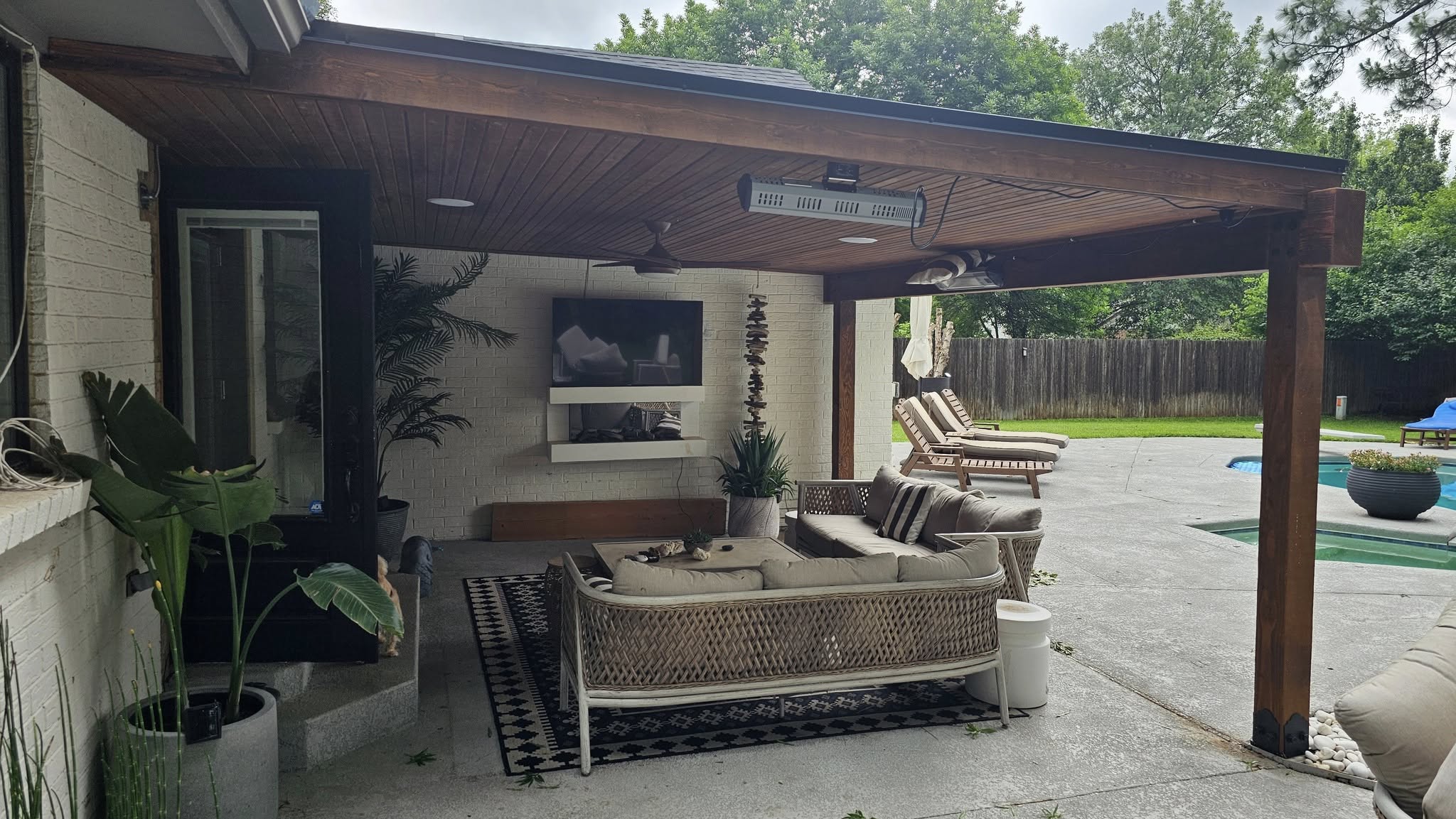 An outdoor patio with furniture, a TV, and a pool is shown.