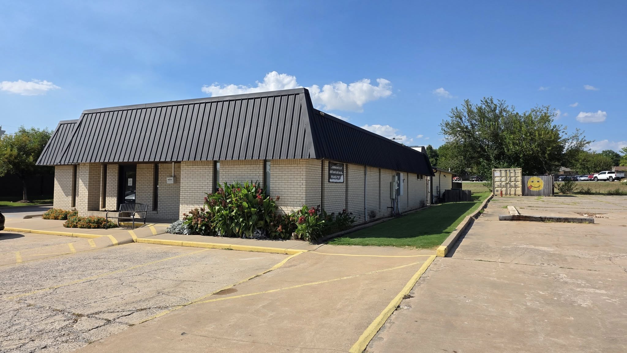 A brick building with a metal roof and a parking lot is shown.