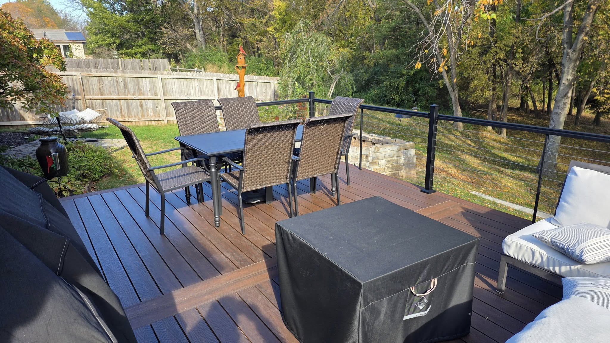 A backyard deck with a dining set, fire pit cover, and seating area.