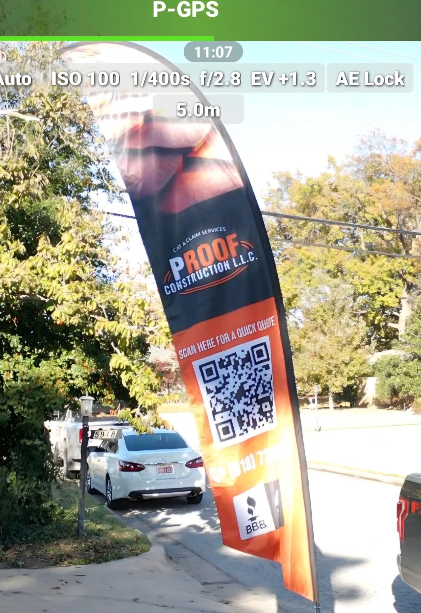 A banner for "Proof Construction L.L.C." is displayed outdoors near a white car and a truck.