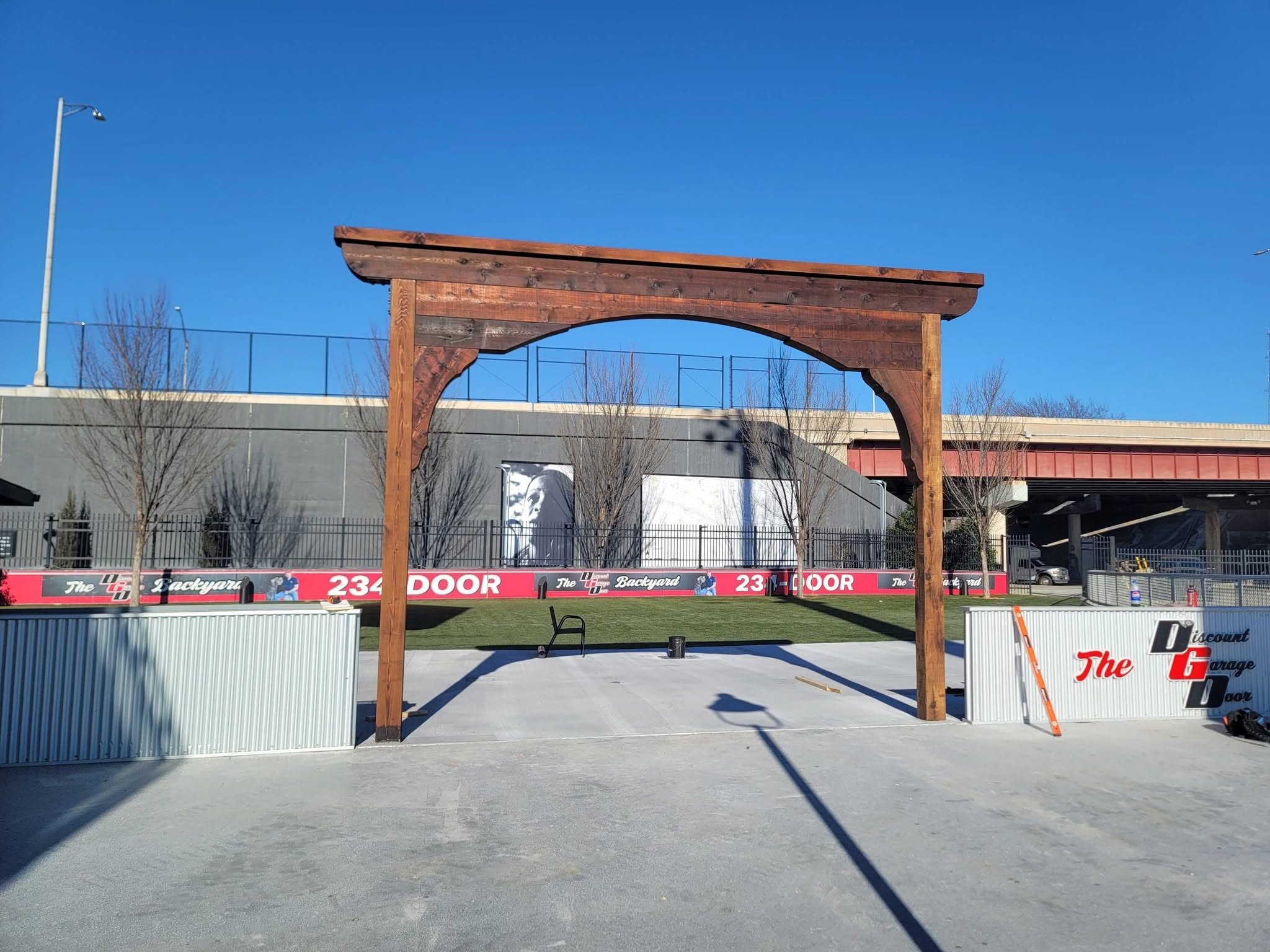 A wooden archway stands in an outdoor area with a clear blue sky.