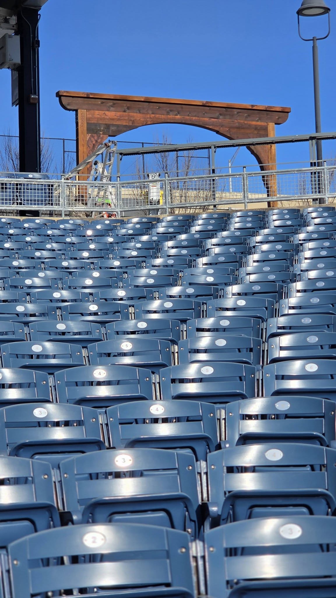 Empty blue stadium seats are shown in front of a wooden archway.