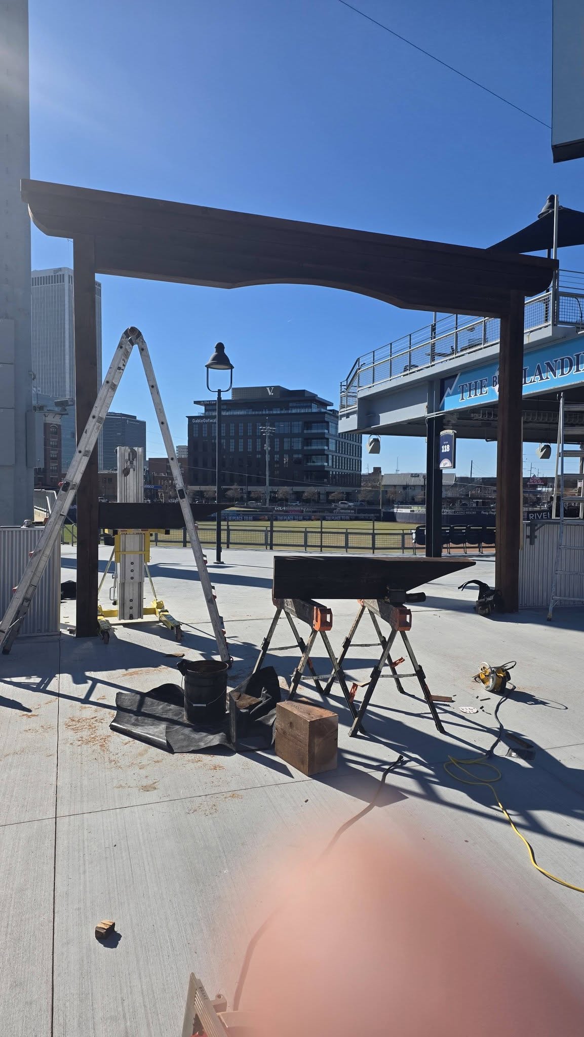 Construction of a wooden structure is underway outdoors with tools and materials present.