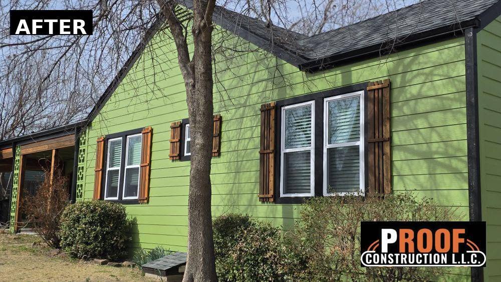 A bright green house with wooden shutters and a construction company logo.
