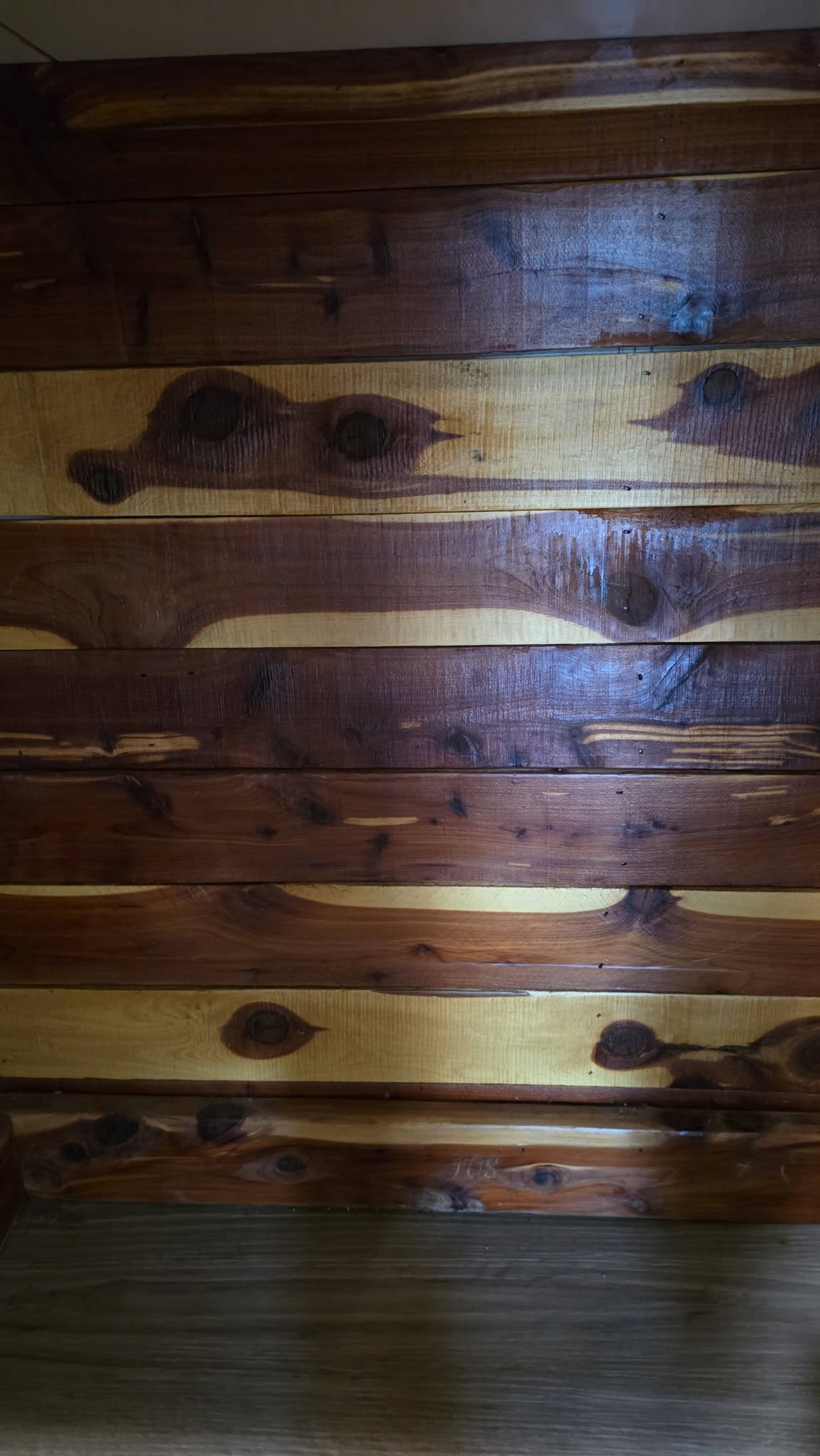 A close-up shot of a wooden wall with alternating dark and light planks.