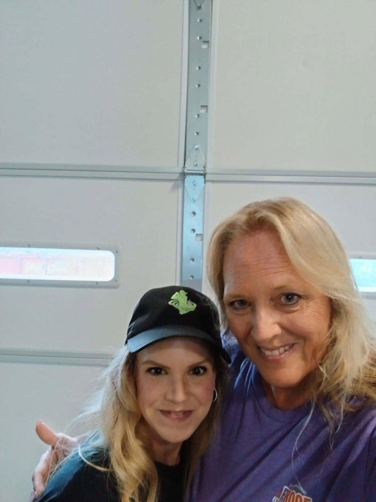 Two women smile for a selfie in front of a garage door.