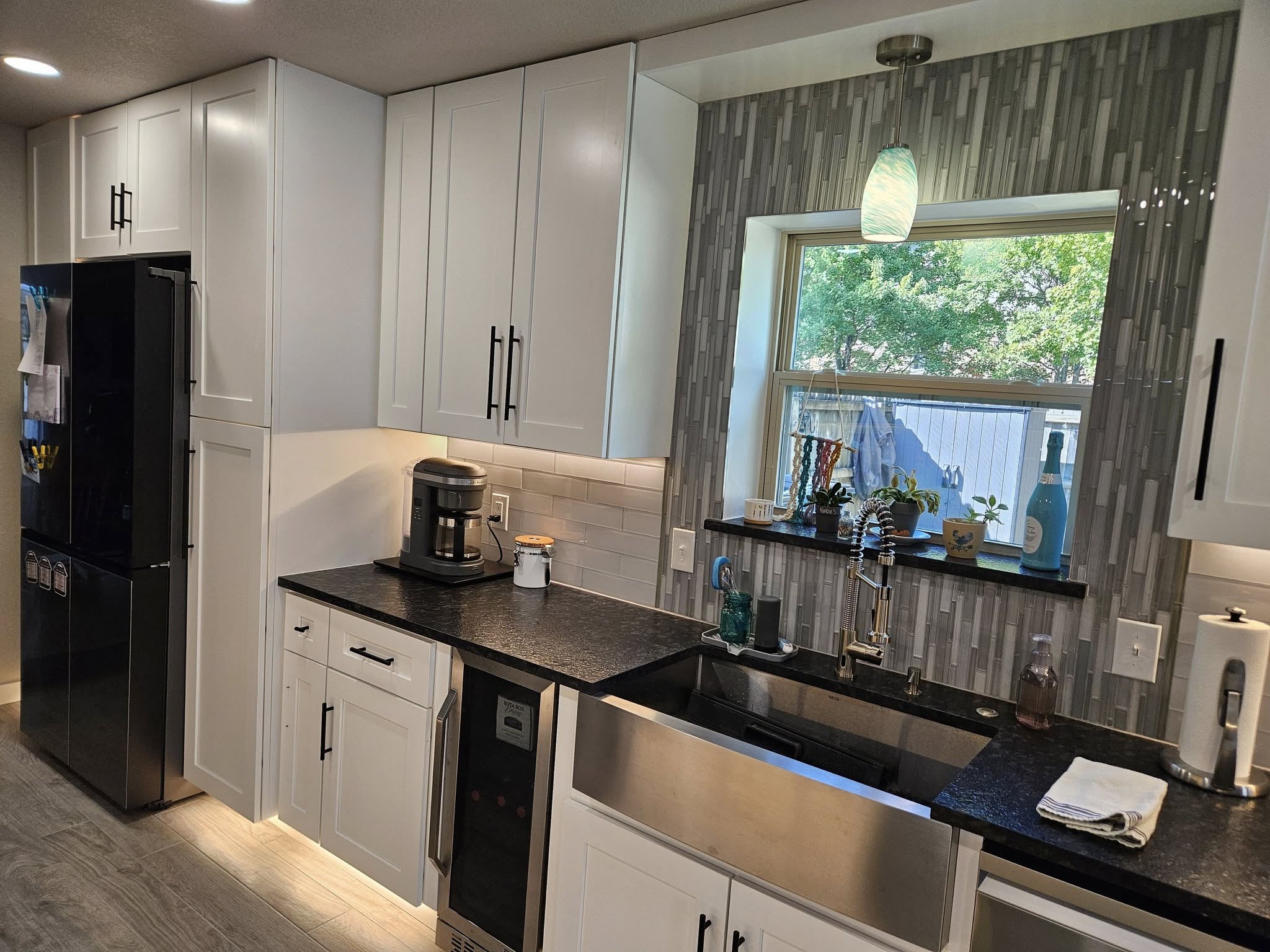 A modern kitchen with white cabinets, black countertops, and stainless steel appliances.