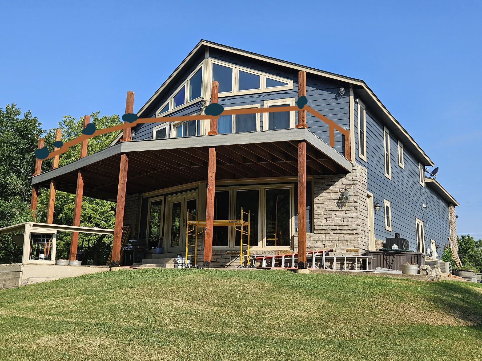 A house under construction with a deck and railing being installed.