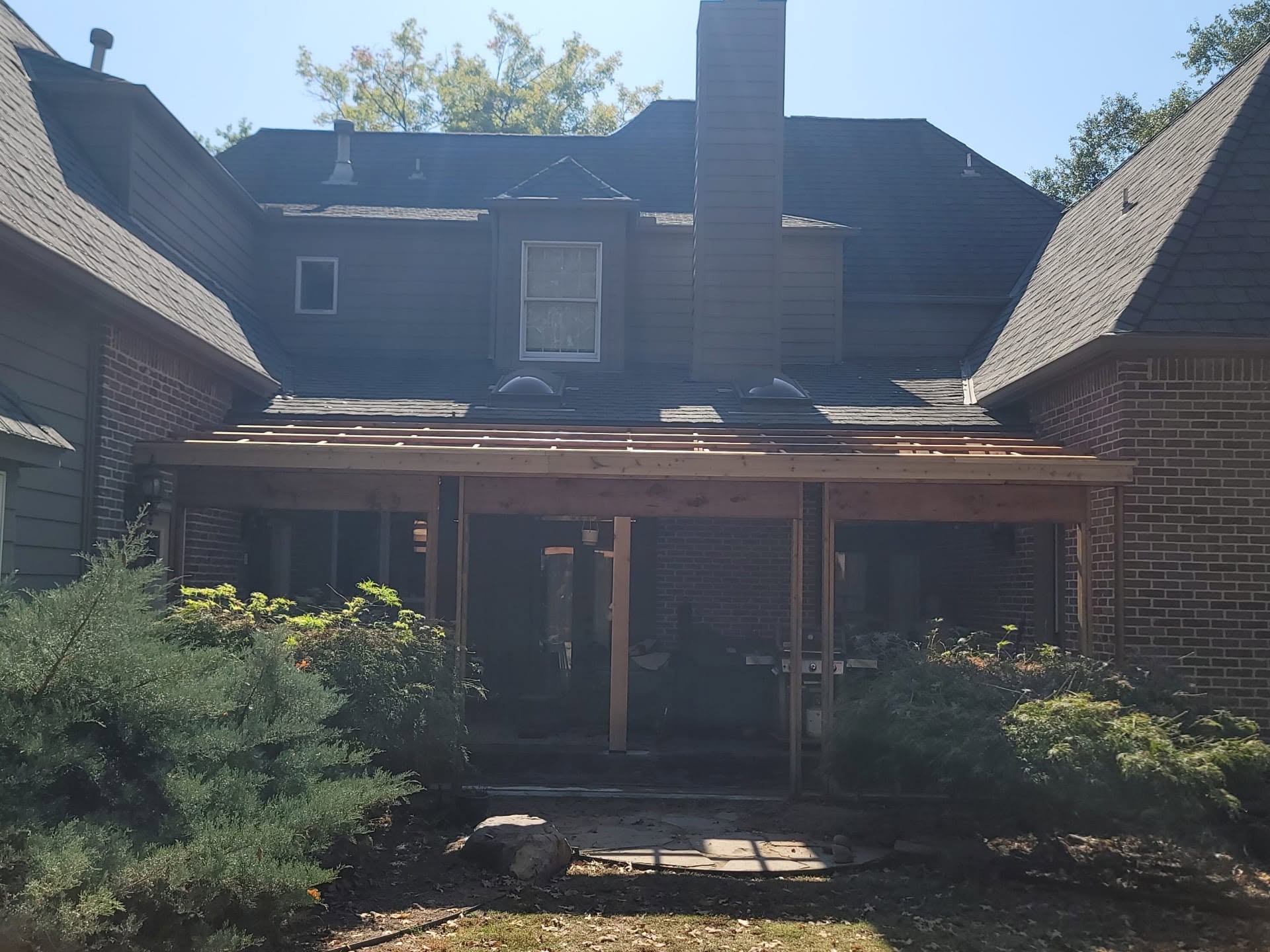 A house under construction with a new wooden patio roof.